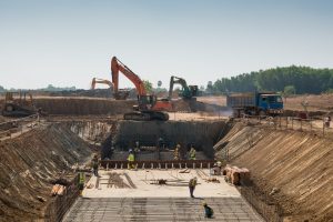 A close shot of heavy machines and construction workers working on a building